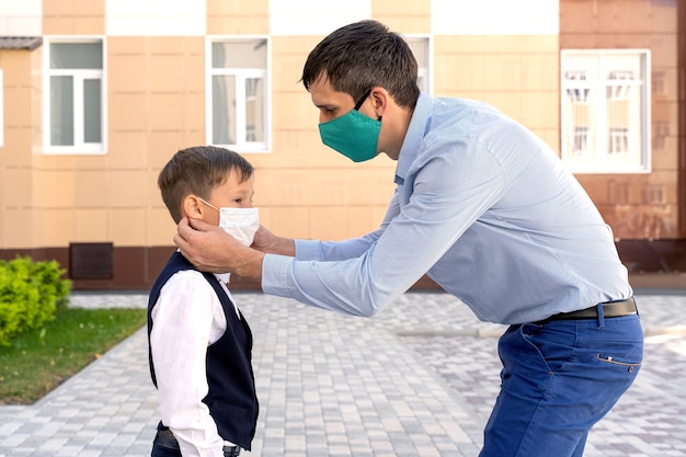 Papa met un masque sur un écolier pendant une pandémie