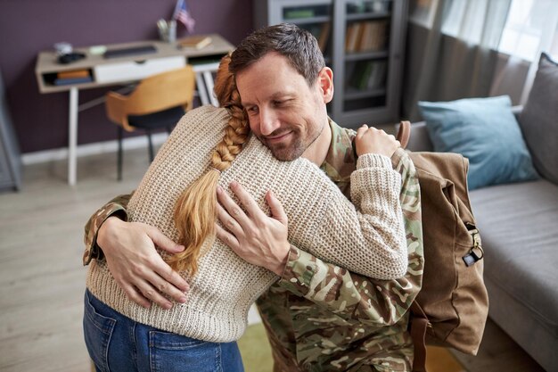 Papa militaire rentre à la maison et embrasse sa fille dans un moment de liaison