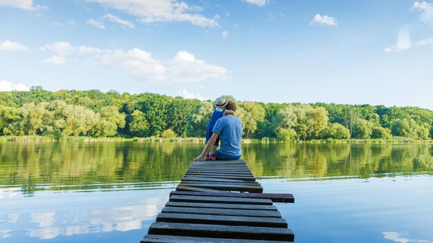 Papa et une petite fille en salopette se détendent au bord de la rivière Vue arrière copie espace