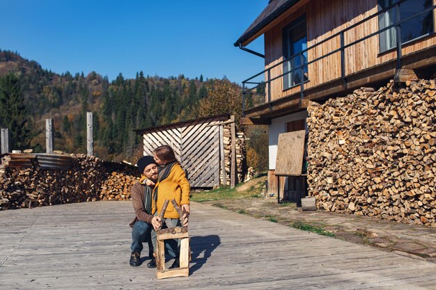 Papa et sa fille construisent ensemble une maison en rondins de jouets sur une terrasse dans les montagnes par une journée d'automne ensoleillée. fille embrasse père