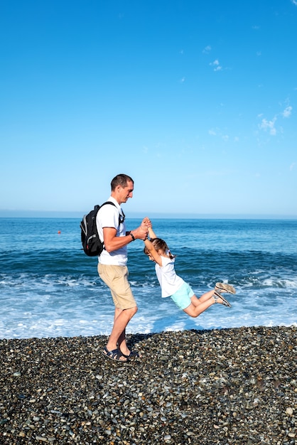 Papa et sa fille jouent au bord de la mer. le concept de vacances communes avec un enfant. fête des pères