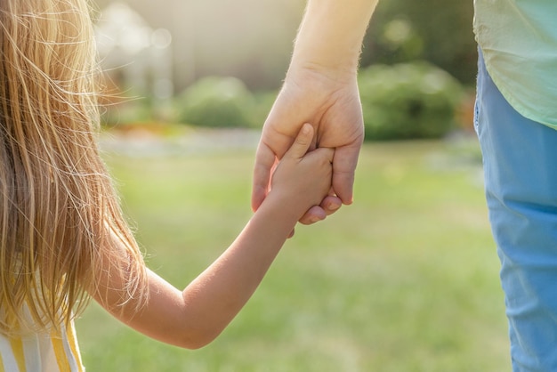 Photo papa et sa fille marchent à l'extérieur et se tiennent la main le concept de confiance en gros plan