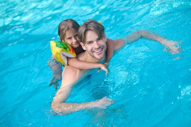 Papa et sa fille nageant ensemble dans une piscine