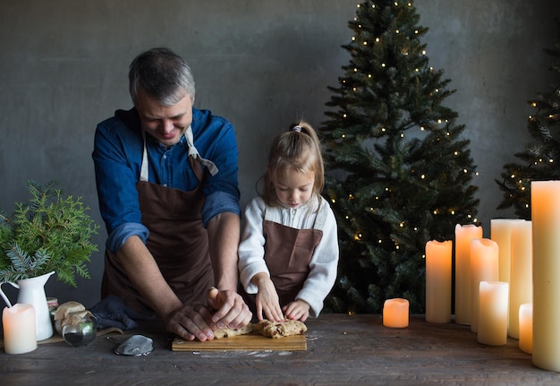 Papa et sa fille pétrissent la pâte ensemble sur la table et préparent des friandises de Noël Traditions familiales