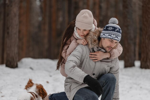 Papa avec sa fille et ses chiens marchent et jouent dans la promenade familiale de la forêt d'hiver