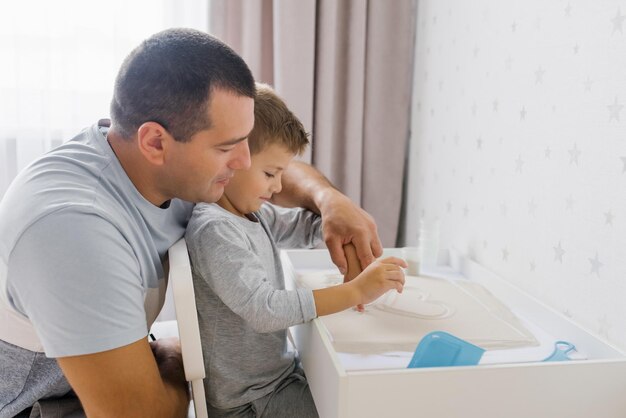 Papa et son bébé jouent à la maison avec du sable de quartz