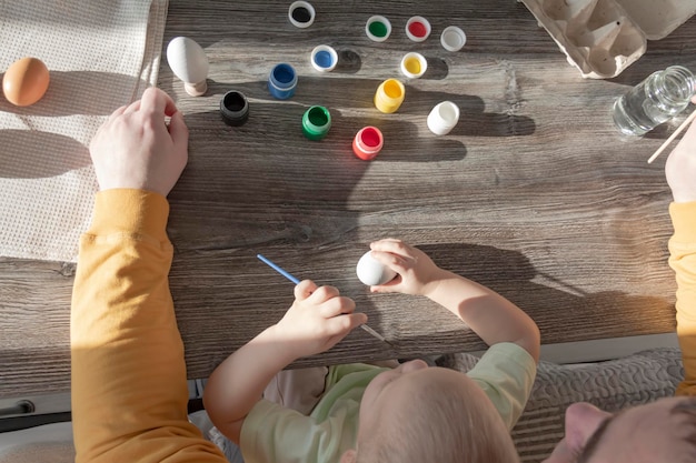 Papa et son enfant peignent des oeufs pour Pâques