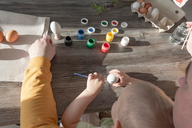 Papa et son enfant peignent des oeufs pour Pâques