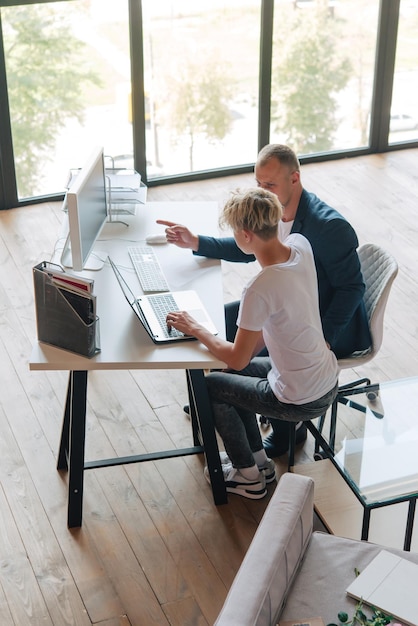 Papa et son fils adolescent travaillent à l'ordinateur Communication en ligne Enseignant et élève