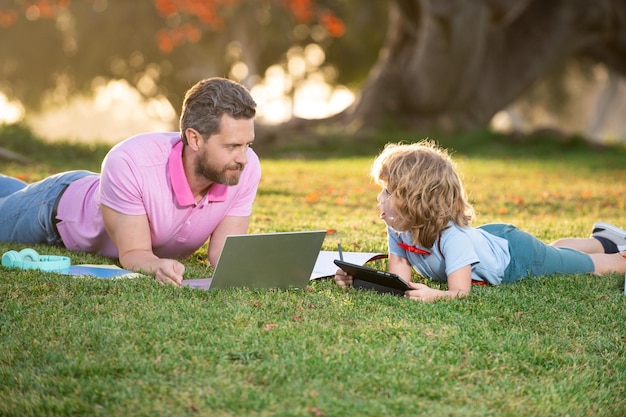 Papa et son fils à l'aide d'un tablet pc dans un parc par beau temps blogging d'éducation en plein air