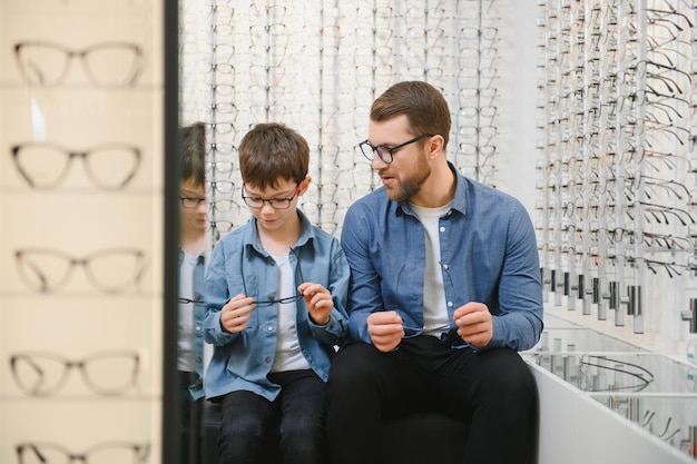 Papa et son fils choisissent de nouvelles lunettes élégantes dans un magasin d'optique Concept de soins de la vue