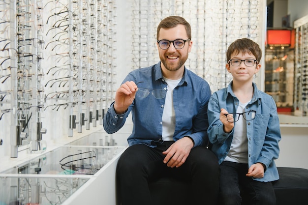 Papa et son fils choisissent de nouvelles lunettes élégantes dans un magasin d'optique Concept de soins de la vue