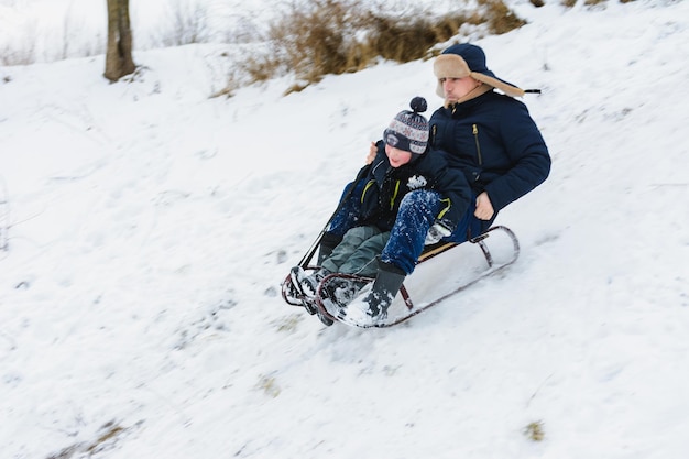 Papa et son fils font de la luge, bébé est amusant