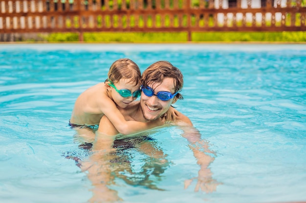 Papa et son fils en lunettes de natation s'amusent dans la piscine