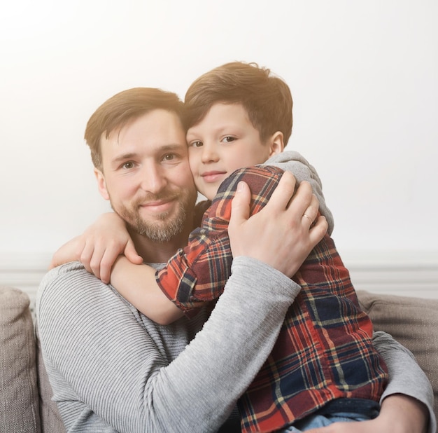 Papa et son fils passent du temps ensemble et s'embrassent sur un canapé à la maison