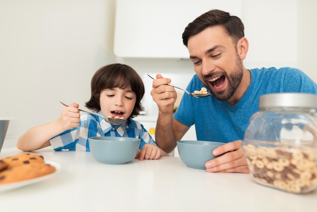 Papa et son fils prennent le petit déjeuner dans la cuisine ensemble.