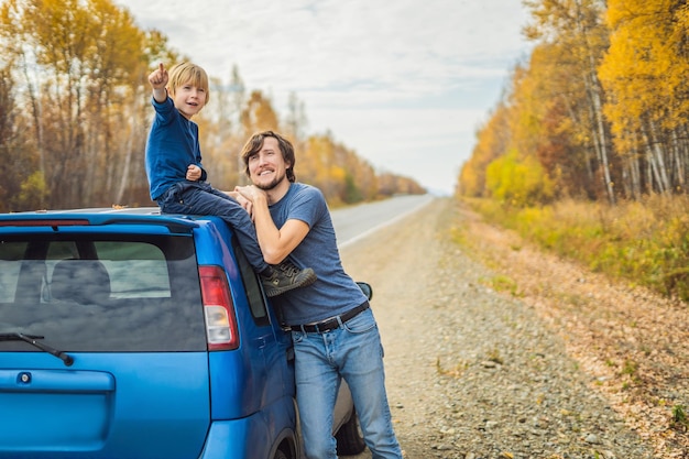 Papa et son fils se reposent sur le bord de la route lors d'un voyage en voiture. Voyage en voiture avec concept d'enfants.