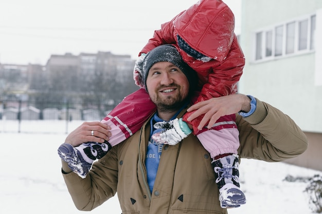 Papa tient une petite fille sur ses épaules.