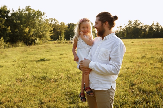 Papa tient sa fille dans ses bras. promenade d'été