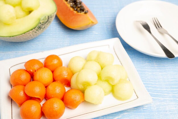 Photo papaye fraîche et melon japonais frais coupé en forme de cercle servant sur une assiette blanche