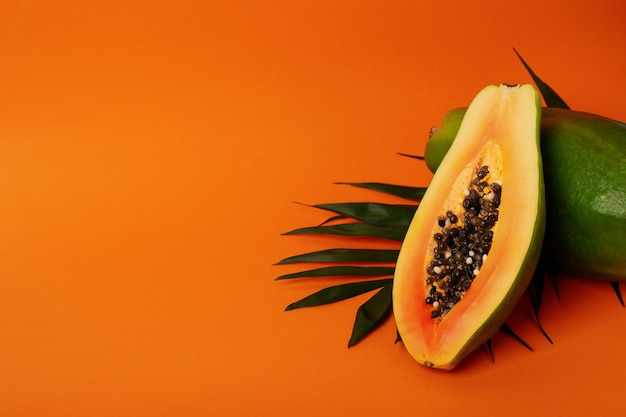Photo papaye mûre avec des feuilles sur fond orange