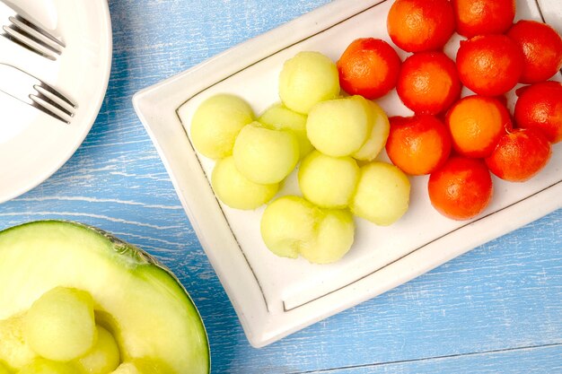 Papaye mûre et melon japonais coupés en formes de cercle servant sur une assiette blanche sur une table en bois