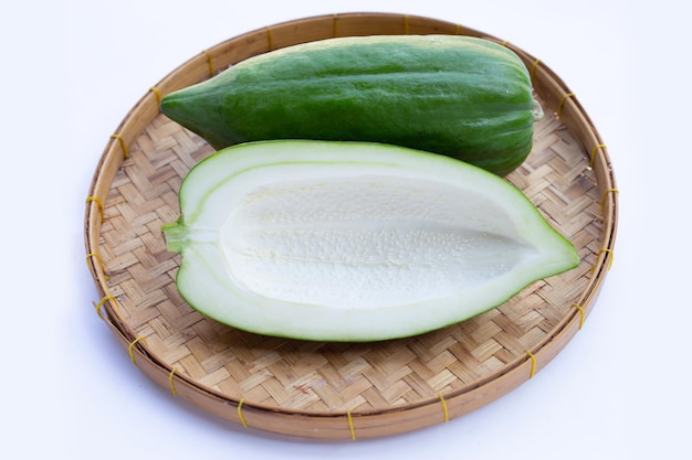 Papaye verte dans un panier de bambou sur fond blanc.