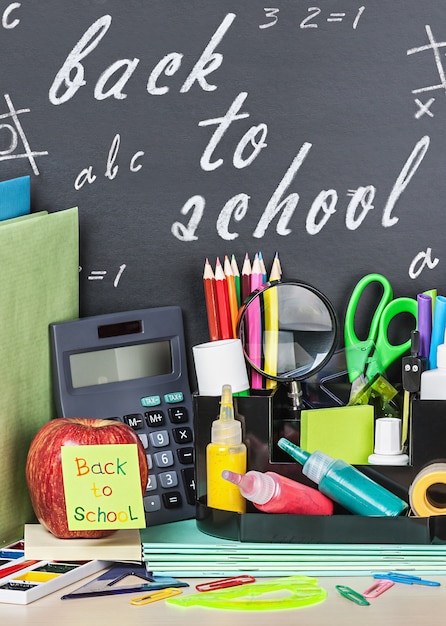 Papeterie scolaire posée sur un fond de tableau