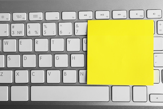 Papier adhésif jaune vide sur le clavier sur fond clair