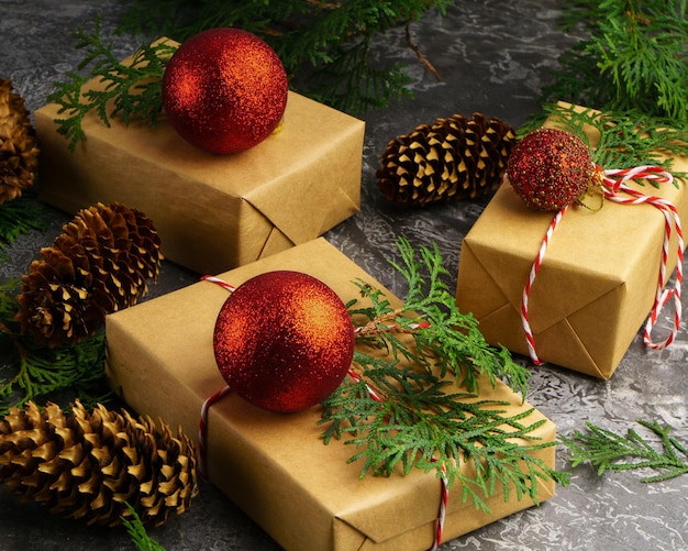 Le papier artisanal présente des boîtes de corde de sapin branche de boules rouges de fruits orange tranchés à sec sur fond de béton. Vue de dessus du concept de cadeau de Noël. Contexte de préparation du nouvel an.