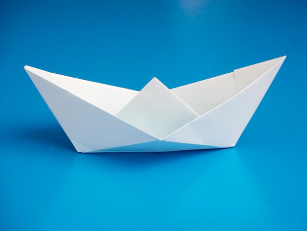 Papier de bateau blanc origami concept commercial minimal sur fond bleu
