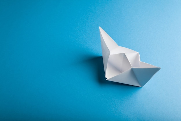 Papier bateau origami sur la surface bleue