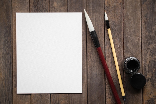 Papier blanc abstrait avec pinceau de calligraphie en bambou et pierre à encre sur une vieille image de table en bois pour ajouter du texte ou une carte de voeux Nouvel an chinois Texte de peinture traditionnelle chinoise