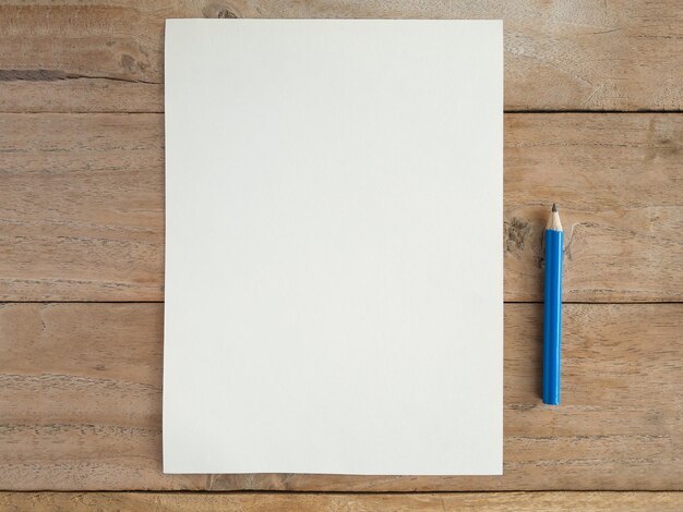 Photo un papier blanc avec un crayon sur une table en bois.