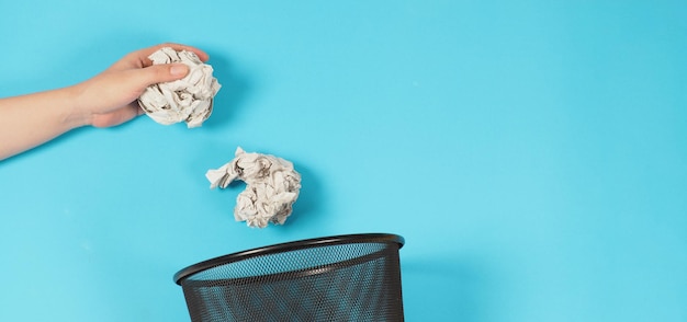 Photo le papier blanc froissé est mutilé dans la main de l'homme et du papier blanc froissé et une poubelle sur fond bleu