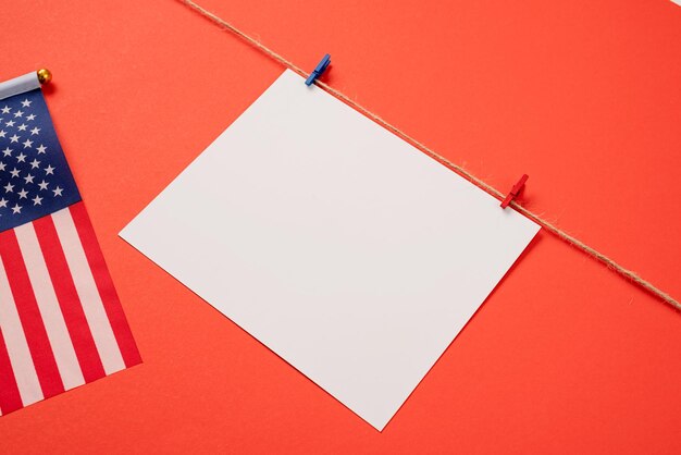 Papier blanc vierge pour la conception de maquettes avec des clips rouges et bleus sur fond rouge