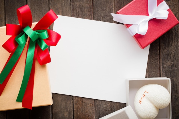 Papier blanc vierge valentines ou carte de voeux de Noël avec ruban rouge sur une vieille table en bois sombre image d'arrière-plan pour ajouter un message texte