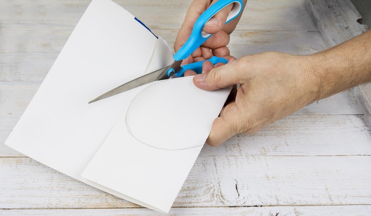 Photo papier de coupe à la main coupé avec des ciseaux sur la table