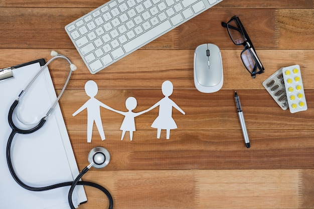 Photo papier découpé chaîne familiale avec médecine, souris, clavier, stéthoscope, presse-papiers et lunettes