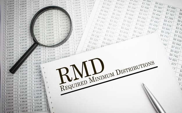 Papier avec les distributions minimales requises RMD sur une table avec un graphique à plumes et une loupe