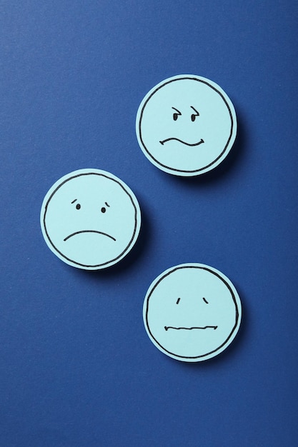 Papier avec emoji triste sur la vue de dessus de fond bleu foncé