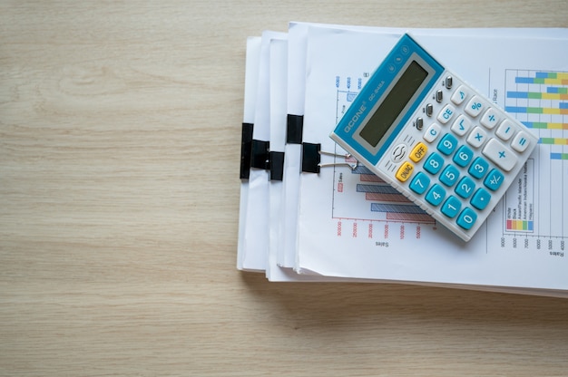 Papier de rapport financier et machine de calcul sur le bureau de table, concepts de finance et de comptabilité