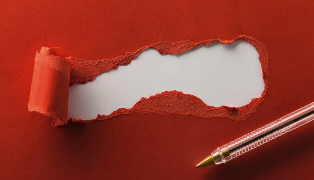 Papier rouge déchiré avec un espace pour votre texte et votre stylo se bouchent