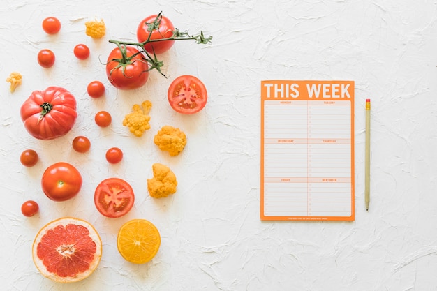 Papier de la semaine de l&#39;alimentation avec un crayon et des légumes sains sur fond blanc