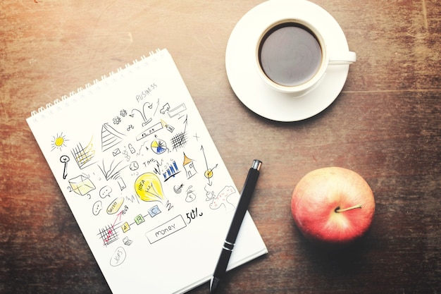 Papier avec stylo, tasse à café et pomme rouge sur table en bois