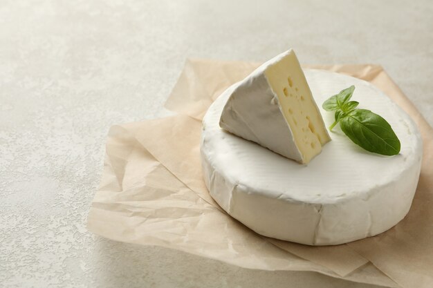 Papier sulfurisé avec du fromage camembert sur fond texturé blanc