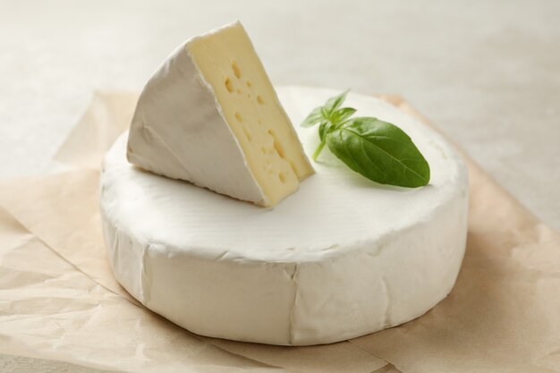 Papier sulfurisé avec du fromage camembert sur fond texturé blanc