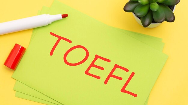 Papier avec texte TOEFL sur fond jaune avec papeterie