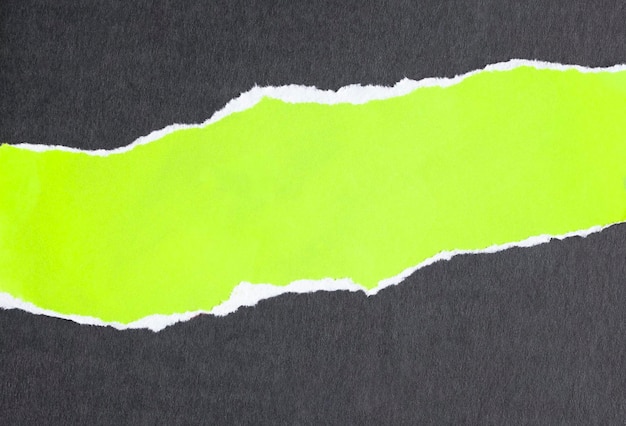 Papier vert fluorescent déchiré sur fond noir