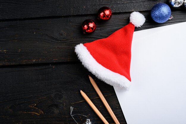 Papier vide avec ensemble de décoration d'arbre de Noël, vue de dessus à plat, avec espace de copie pour le texte, sur fond de table en bois noir